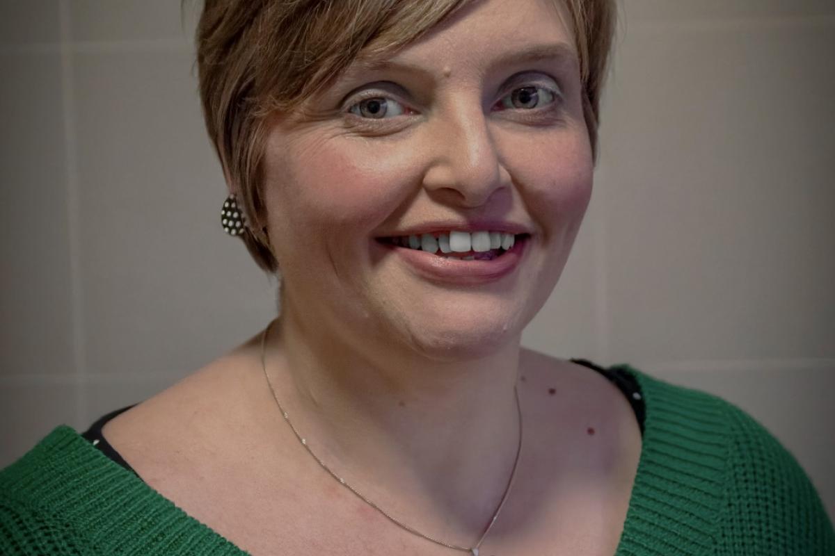 Rachael smiling wearing a green v-neck jumper