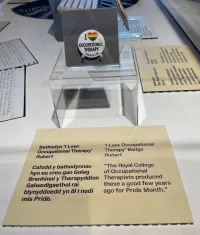A pride bade that says 'I [rainbow heart] occupational therapy' in a museum exhibition