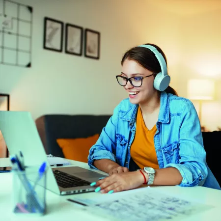 women sat with headphones on looking at a laptop screen