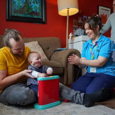 occupational therapist and parents smiling with baby