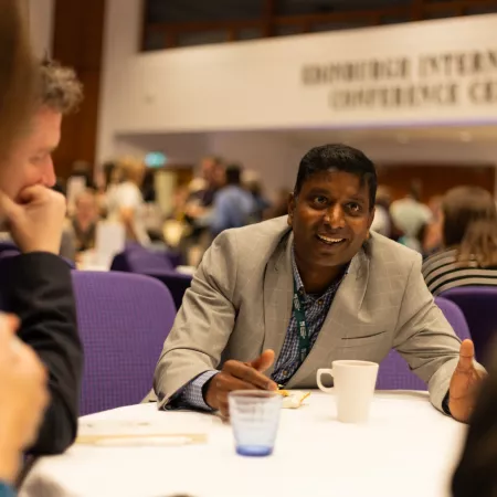 Smiling man and people sitting around a table with coffee