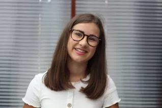 Georgina Vine, smiling with glasses and white top